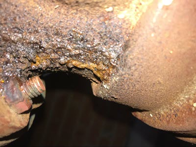 A close up of a rusted and dripping sewer pipe